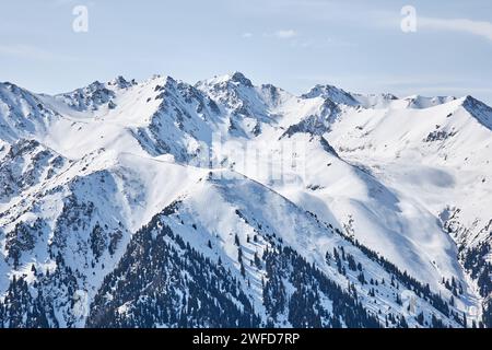 Vista panoramica dalla cima della pista sulle alte montagne innevate. Stazione sciistica di Karakol in Kirghizistan. Paesaggio naturale invernale, catena montuosa Foto Stock