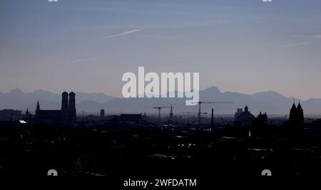 Monaco, Germania. 30 gennaio 2024. I contorni della Frauenkirche (l) e delle gru da costruzione si stagliano contro il panorama delle Alpi. Credito: Karl-Josef Hildenbrand/dpa/Alamy Live News Foto Stock