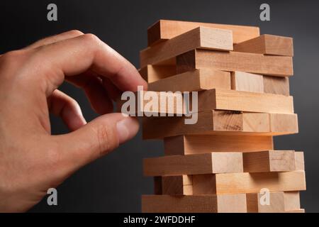 La pianificazione del rischio e della strategia nel business, imprenditore ingegnere e gioco d'azzardo posizionando il blocco di legno su una torre. Foto Stock