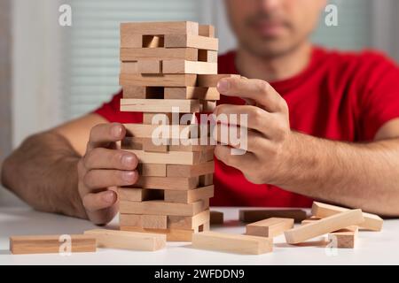 La pianificazione del rischio e della strategia nel business, imprenditore ingegnere e gioco d'azzardo posizionando il blocco di legno su una torre. Foto Stock