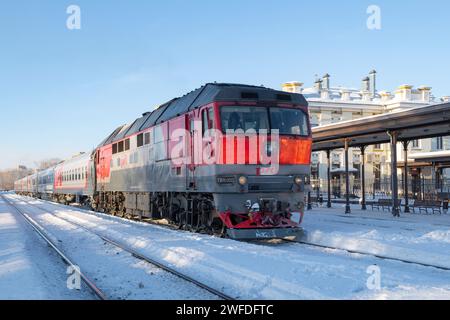 RYBINSK, RUSSIA - 3 GENNAIO 2024: Treno passeggeri con locomotiva diesel TEP-70 sulla stazione di Rybinsk in una soleggiata giornata di gennaio Foto Stock