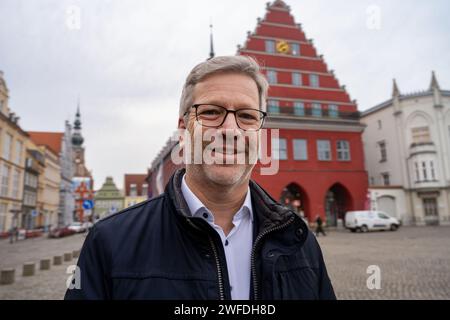 Greifswald, Germania. 30 gennaio 2024. Stefan Fassbinder (Alliance 90/The Green), sindaco di Greifswald, si trova di fronte al municipio. Ha vinto uno dei quattro titoli di "Sindaco Mondiale" per il 2023. Questo in riconoscimento del suo sostegno e della sua cooperazione con i comuni di Ucraina, Polonia e Brasile, la City Mayors Foundation ha annunciato lunedì sera a Londra. Ha anche offerto generoso aiuto ai rifugiati dall'Ucraina. (Al Lord Mayor di Greifswald onorato con il titolo di "sindaco mondiale") credito: Stefan Sauer/dpa/Alamy Live News Foto Stock