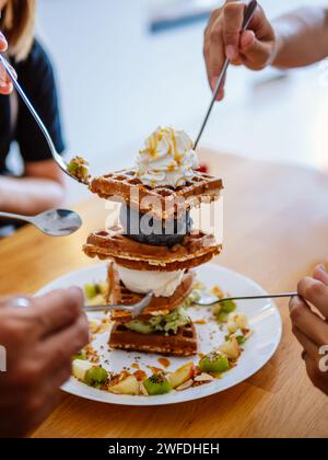 Waffle, gaufre o wafel o waffle con frutta, gelato e farcitura. Dolce Indulgence. Gelato appena sfornato waffle con deliziosi condimenti su legno Foto Stock