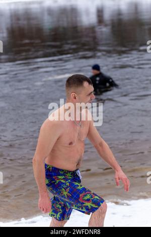 Grodno, Bielorussia - 28 gennaio 2024: Il giovane si tuffa nel fiume in inverno durante la tradizionale corsa annuale del temper-fest. Bagnino subacqueo Foto Stock