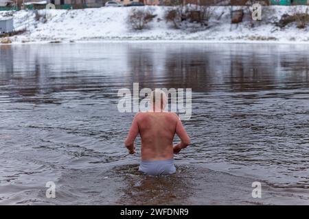 Grodno, Bielorussia - 28 gennaio 2024: Il giovane si tuffa nel fiume in inverno durante la tradizionale corsa annuale del temper-fest. Bagnino subacqueo Foto Stock