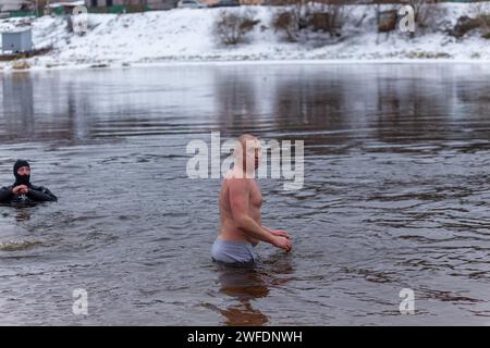 Grodno, Bielorussia - 28 gennaio 2024: Il giovane si tuffa nel fiume in inverno durante la tradizionale corsa annuale del temper-fest. Bagnino subacqueo Foto Stock