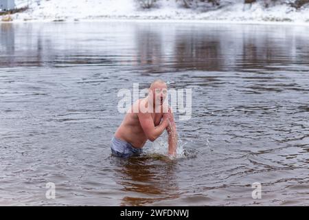 Grodno, Bielorussia - 28 gennaio 2024: Il giovane si tuffa nel fiume in inverno durante la tradizionale corsa annuale del temper-fest. Bagnino subacqueo Foto Stock