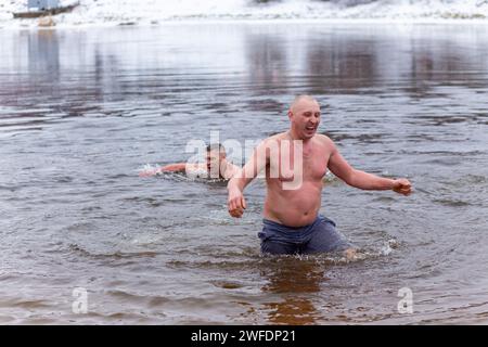 Grodno, Bielorussia - 28 gennaio 2024: Il giovane si tuffa nel fiume in inverno durante la tradizionale corsa annuale del temper-fest. Bagnino subacqueo Foto Stock