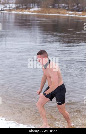 Grodno, Bielorussia - 28 gennaio 2024: Il giovane si tuffa nel fiume in inverno durante la tradizionale corsa annuale del temper-fest. Bagnino subacqueo Foto Stock