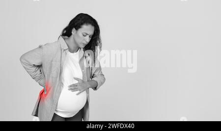 Donna incinta con il mal di schiena in piedi in Studio Foto Stock
