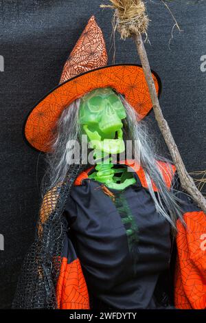 Mostra di Halloween di scheletro di plastica verde drappeggiato in costume da strega nero e arancione con cappello a punta e scopa, Quebec, Canada. Foto Stock