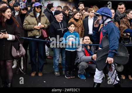 Gente che fissa il fantino Guillaume Martin, dopo la sua gara, all'ippodromo di Vincennes. La gara di trotto più conosciuta al mondo, il Prix D'Amerique Legend Race, si è svolta nell'ippodromo di Vincennes, alla periferia di Parigi. Questa razza rimane una delle più importanti corse equestri al mondo, seguita da milioni di spettatori. Clement Duvaldestin e il suo cavallo Idao de Tillard furono i vincitori del Grand Prix d'Amerique 2024. Foto Stock