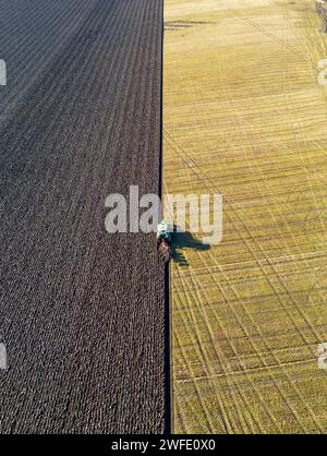 Vista aerea con droni di un trattore che ara un campo, Linlithgow, West Lothian, Scozia Foto Stock