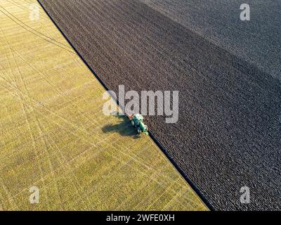 Vista aerea con droni di un trattore che ara un campo, Linlithgow, West Lothian, Scozia Foto Stock