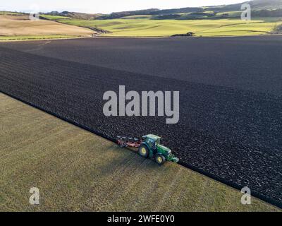 Vista aerea con droni di un trattore che ara un campo, Linlithgow, West Lothian, Scozia Foto Stock
