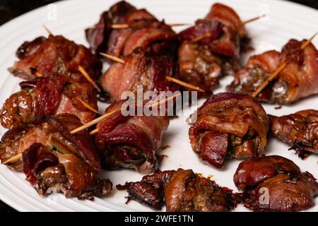 Fegato di pollo cotto avvolto con pancetta. Kebab di fegato arrosto con su un piatto bianco. Foto Stock