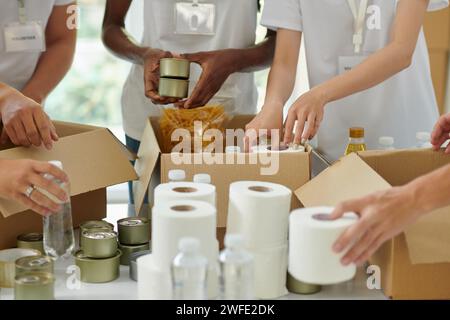 Volontari che imballano le merci donate in scatole di cartone Foto Stock