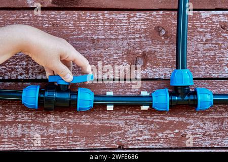 I raccordi per tubi con morsetti a vite di compressione, valvola a sfera e triplo raccordo collegano i tubi di alimentazione dell'acqua alla rete. Foto Stock
