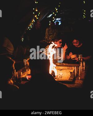 Un gruppo di individui si radunò intorno a un accogliente fuoco durante le ore notturne Foto Stock