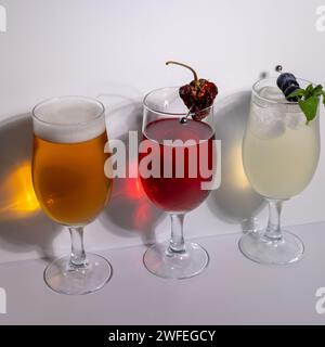 Cocktail e birra preparati e guarniti in studio sullo sfondo bianco Foto Stock