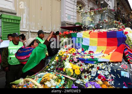 La Paz, BOLIVIA; 24 gennaio 2015. Una signora indigena lancia petali su un'antica illa (o statua) di un Ekeko (un dio Aymara dell'abbondanza) mentre viene sfilata per le strade di la Paz per celebrare la sua prima apparizione al festival Alasitas, che inizia oggi. La statua ha circa 2000 anni ed è stata realizzata dalla cultura Pucara. È stato portato dal sito archeologico di Tiwanaku in Svizzera nel 1858, e restituito in Bolivia dal Museo di storia di Berna nel novembre 2014. Foto Stock