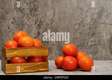 Immagine del prodotto con un cestello di legno pieno di arance e altre in pila, isolato su sfondo grigio. Vitamina c, supercibo, frutta fresca. Foto Stock