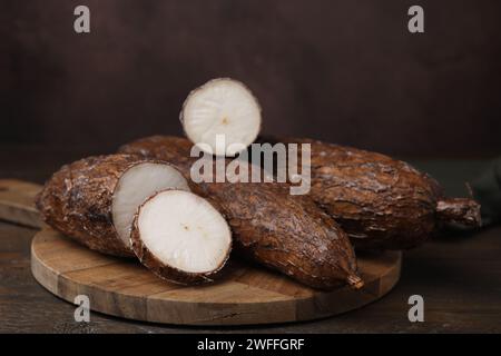 Radici di manioca intere e tagliate su tavola di legno Foto Stock