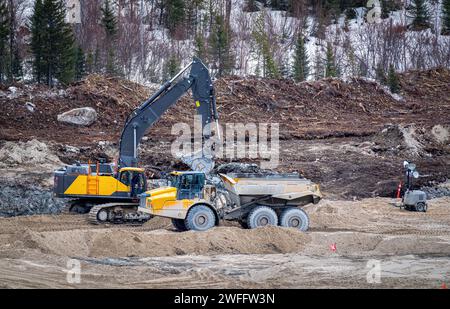 Escavatore e dumper che lavorano in un cantiere, in inverno Foto Stock