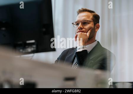 Giovane uomo d'affari sicuro di sé che usa il computer nell'ufficio aziendale Foto Stock