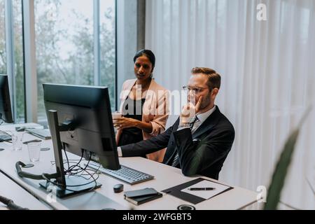 Uomo d'affari sicuro che usa il computer da una donna d'affari in ufficio Foto Stock
