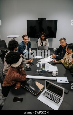 Vista ad alto angolo dei colleghi multirazziali maschi e femmine che discutono di strategia in sala riunioni Foto Stock