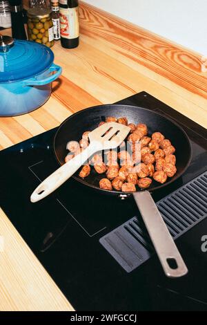 Vista angolare delle polpette in padella sopra il piano cottura in ceramica a casa Foto Stock