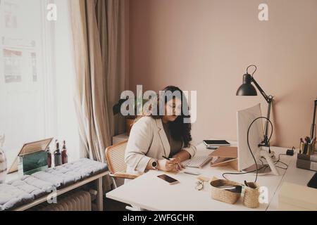 Giovane donna d'affari che lavora seduto alla scrivania in ufficio Foto Stock