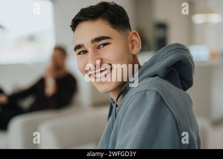 Ritratto di un adolescente sorridente seduto in salotto a casa Foto Stock