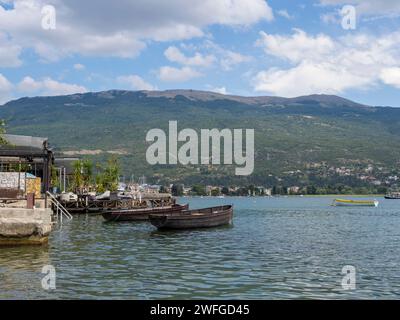 Molte barche ormeggiavano vicino alla riva del lago. Pittoresca vista sull'acqua, sul lungomare e sulle colline. Ohrid, Macedonia del Nord. Foto Stock