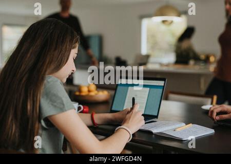 Ragazza pre-adolescente che utilizza un computer portatile mentre è a casa Foto Stock