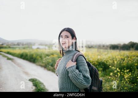 Ritratto di donna con zaino in piedi vicino al campo contro il cielo limpido Foto Stock