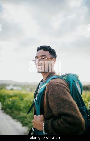 Ritratto di un uomo con zaino che fa trekking sotto il cielo Foto Stock