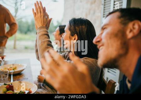 Amici felici che applaudono durante la cena nel patio Foto Stock