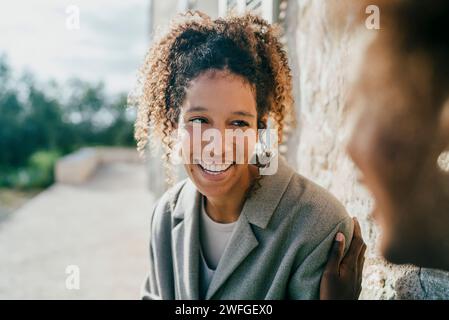 Giovane donna felice seduta con un'amica nel cortile Foto Stock