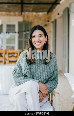 Ritratto di una donna felice seduta sul divano nel patio sul retro Foto Stock