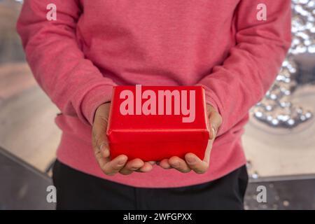 Uomo irriconoscibile con una confezione regalo rossa. Foto Stock