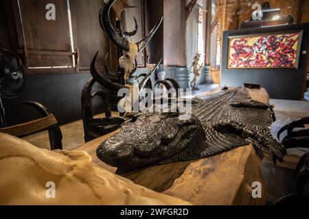 Chiang Rai, Thailandia. 19 gennaio 2024. Una pelle di coccodrillo con la testa all'interno della Casa Nera. Il "Baan Dam Museum", conosciuto anche come la "Casa Nera" e spesso indicato come il "Tempio Nero", non è in realtà un tempio, ma più simile a un museo d'arte e a uno studio con opere d'arte di vari artisti. La "Casa Nera" è anche la più grande collezione al mondo di resti di animali trasformati in mobili. E' stato progettato dal famoso artista thailandese Thawan Duchanee che mescola edifici tradizionali della Tailandia settentrionale con architettura non convenzionale e contemporanea. Credito: SOPA Images Limited/Alamy Live News Foto Stock