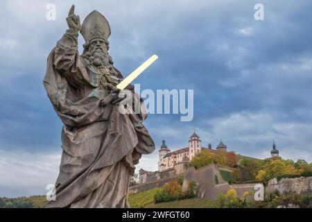 Statua di San Kilian sul vecchio ponte principale con la fortezza di Marienberg sullo sfondo Foto Stock