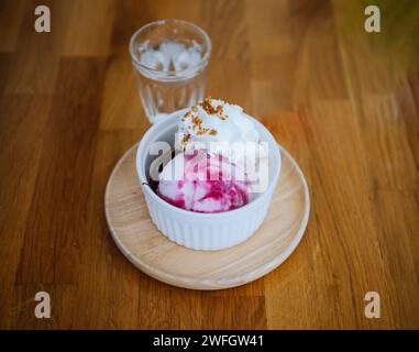 Dessert estivo con gelato, mirtilli, lamponi e mirtilli. Vista dall'alto dello yogurt e del gelato ai mirtilli nella ciotola sul tavolo. Foto Stock