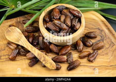 Datteri in una ciotola con foglia di palma e cucchiaio di legno Foto Stock