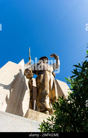 Vista dall'angolo basso di una statua di un soldato con una torcia e una pistola nel monumento Maqam Echahid contro un cielo blu. Foto Stock