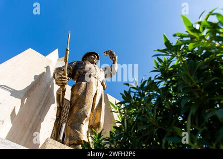 Vista dall'angolo basso di una statua di un soldato con una torcia e una pistola nel monumento Maqam Echahid contro un cielo blu. Foto Stock