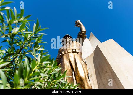 Vista dall'angolo basso di una statua di un soldato che regge una torcia nel monumento Maqam Echahid contro un cielo blu. Foto Stock