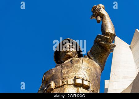 Vista dall'angolo basso di una statua di un soldato che regge una torcia nel monumento Maqam Echahid contro un cielo blu. Foto Stock